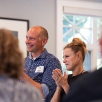 Former coaches Chad and Brie Jedlic clapping at rowing speech